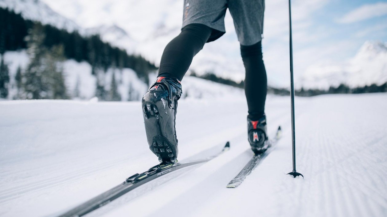 Langlaufvergnügen in der Natur Eine Person beim Langlaufen auf einem verschneiten Weg, Fokus auf Beine und Ski.