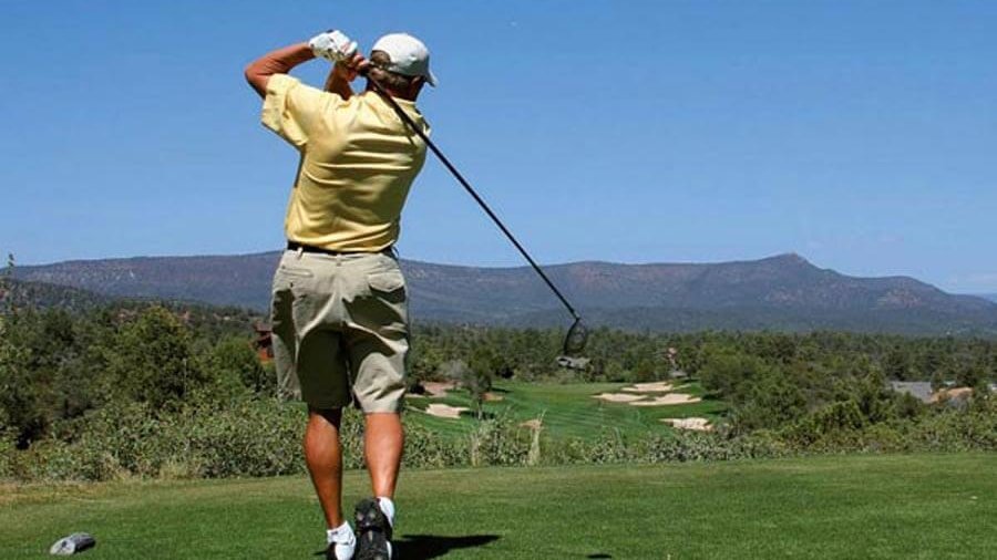 Schlag auf dem Golfplatz Golfer schwingt einen Golfschläger auf einem Golfplatz in den Bergen während des Spiels.