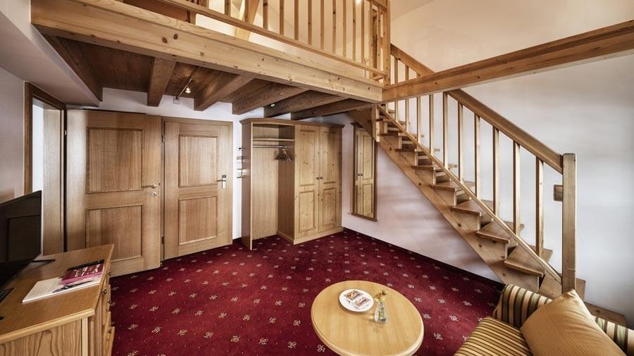 Gemütliche Juniorsuite im Loft-Stil Einladendes Zimmer mit Holzdecke und gemütlicher Sitzecke sowie Treppe zum Loftbereich.
