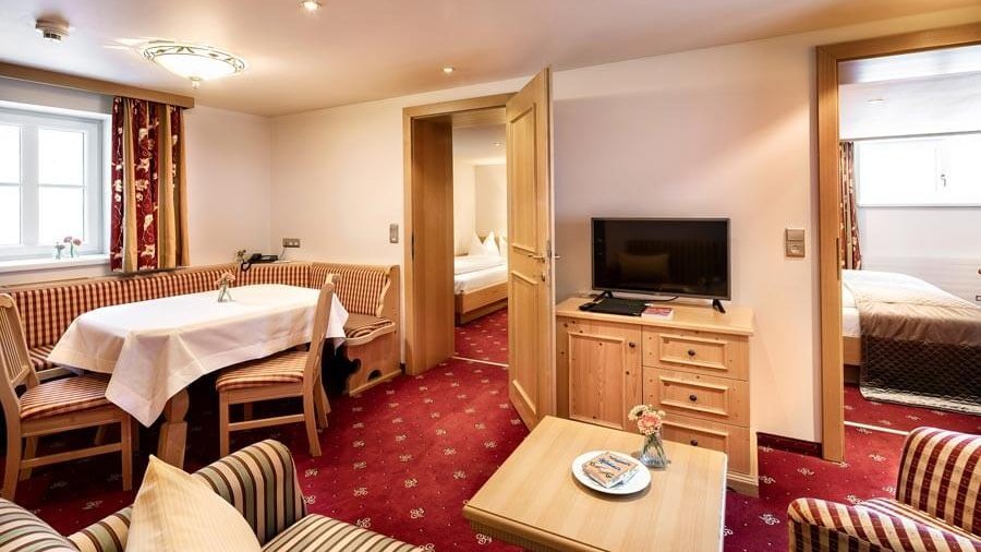Familienzimmer für entspannende Aufenthalte Hotelzimmer mit Sitzbereich und Esstisch, gemütliche Einrichtung mit warmer Farbgestaltung