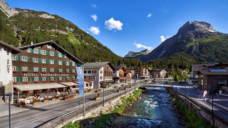 Idyllische Berglandschaft mit Hotel und Fluss Hotel in einer malerischen Umgebung mit Bergen und einem Fluss im Vordergrund, umgeben von Bäumen