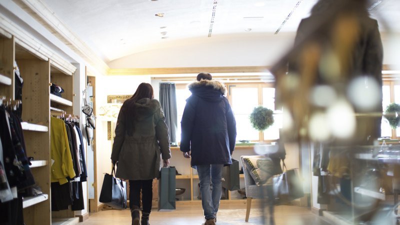 Elegantes Einkaufen im Herzen von Lech Zwei Kunden in einem Einzelhandelsgeschäft, umgeben von Kleidung und Accessoires.