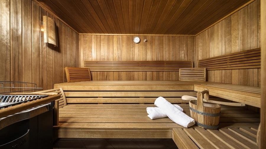 Entspannung in der Holzsauna Die Holzsauna mit Bänken, Aufgusseimer, Handtüchern und Saunasteinofen im Tannbergerhof in Lech © Foto Lehmann
