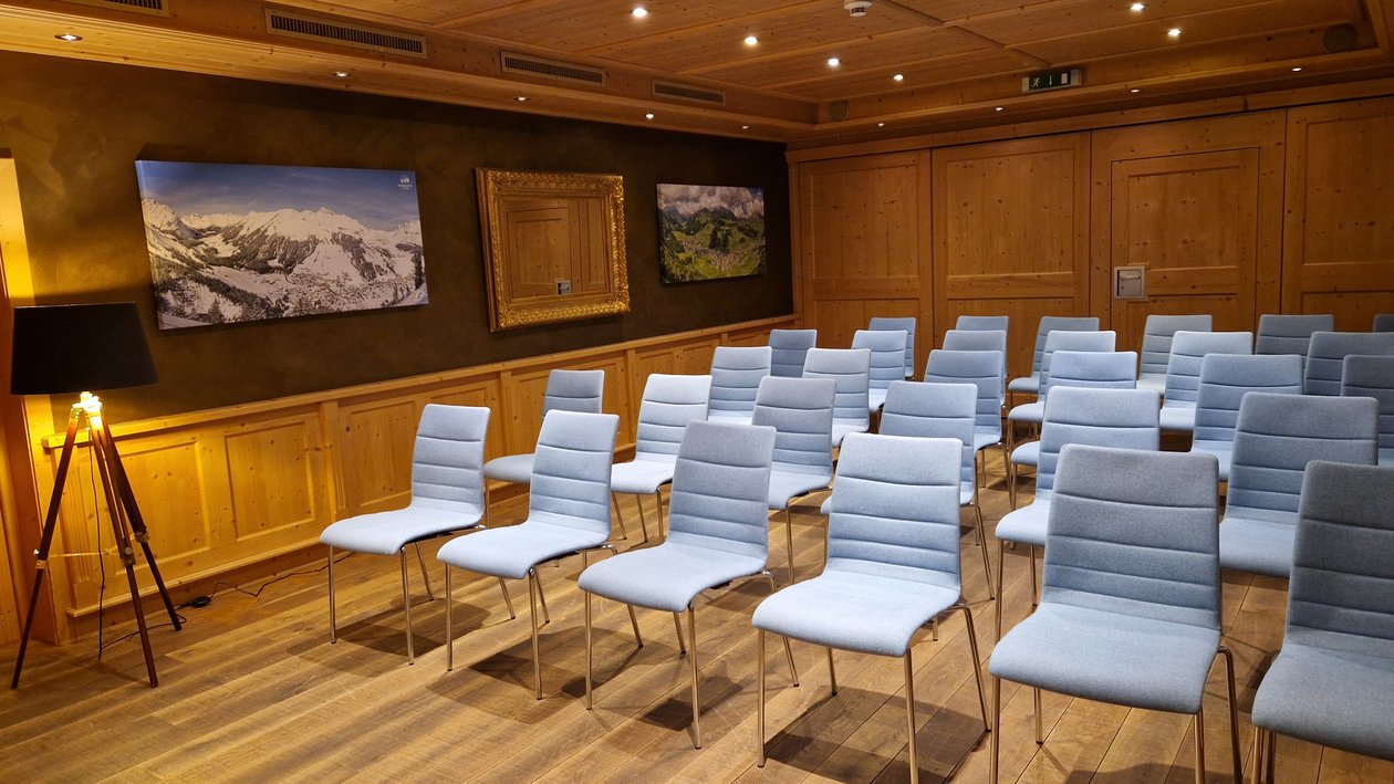 Moderne Konferenzräume für inspirierende Treffen Konferenzraum mit blauen Stühlen, Holzwänden und Berglandschaftsbildern an der Wand