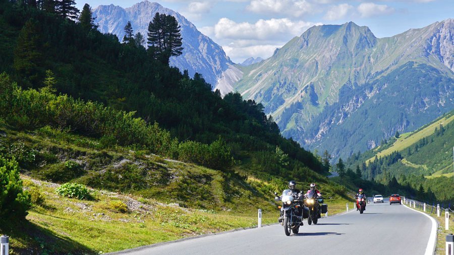 Motorradfahrt durch die Berglandschaft Motorräder auf einer malerischen Bergstraße umgeben von grüner Natur und Bergen im Hintergrund