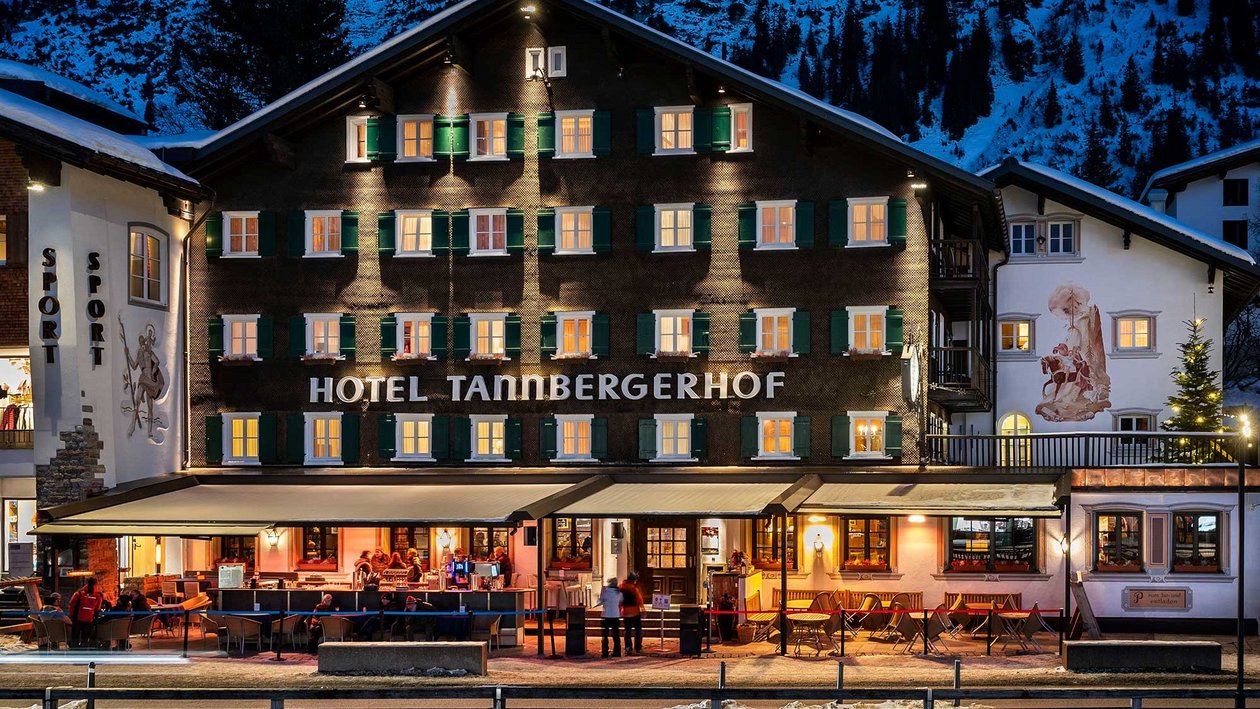 Winterzauber im Tannenbergerhof Mehrstöckiges Hotel mit beleuchteten Fenstern vor schneebedeckten Bergen bei Nacht