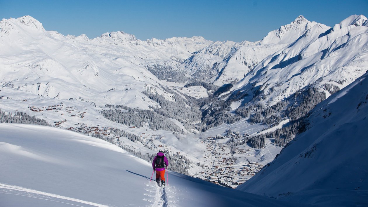 Schneebedecktes Bergabenteuer Skifahrer erklimmt schneebedeckten Hang mit Blick auf das Tal und die Berge im Hintergrund