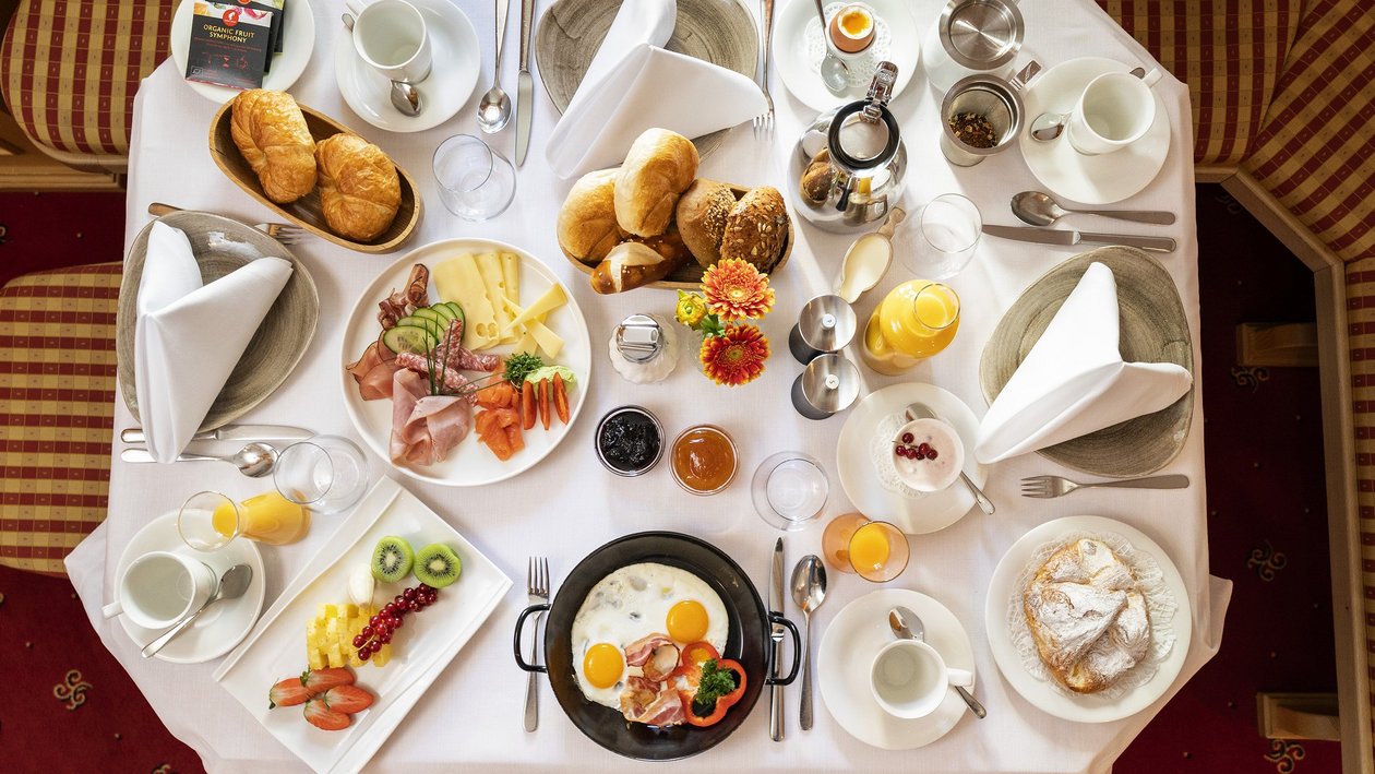 Frühstückserlebnis am Arlberg Ein liebevoll gedeckter Frühstückstisch mit Eiern, Fleisch, Obst und Gebäck für den Genuss am Morgen