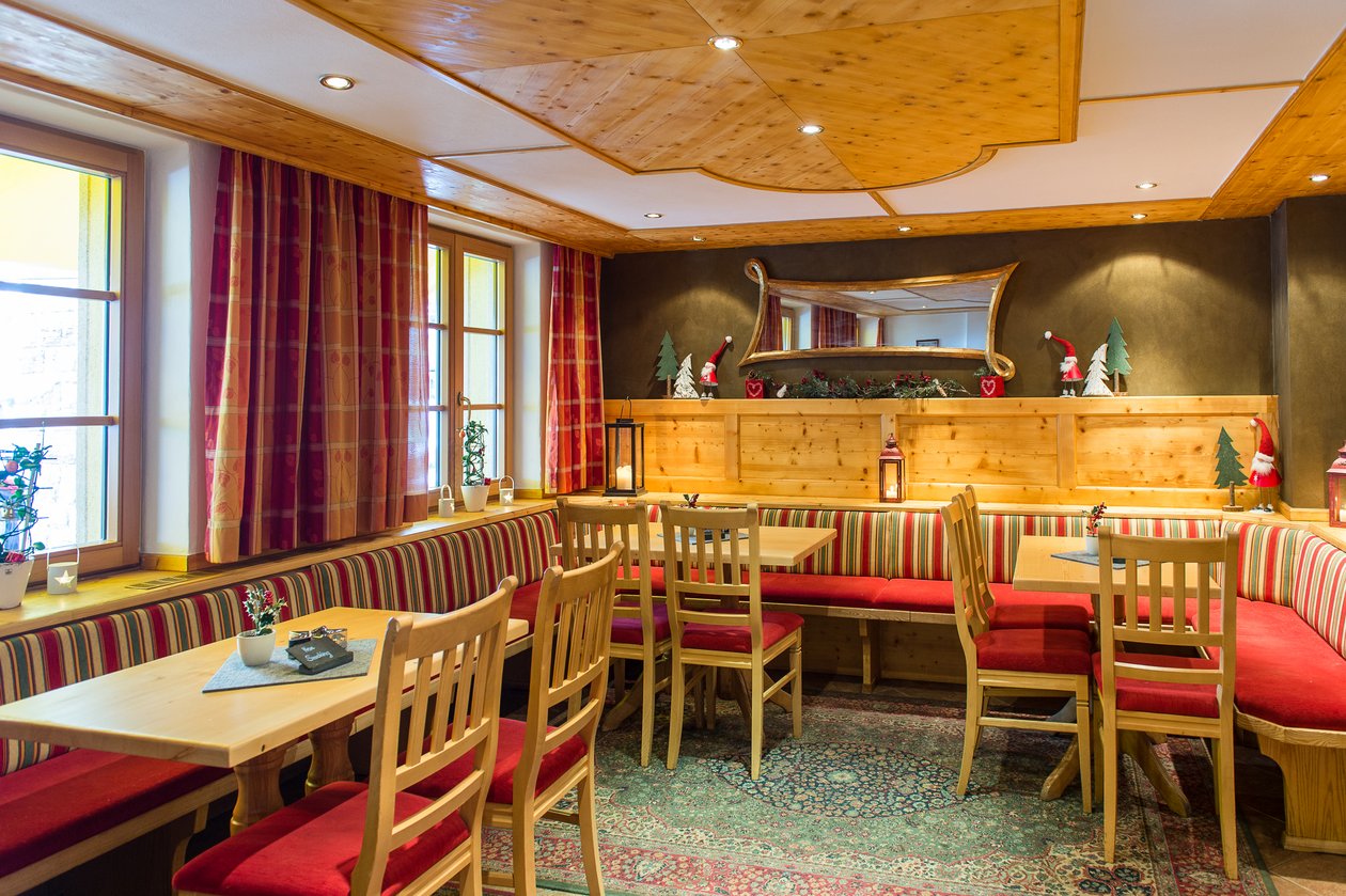 Gemütliches Restaurantambiente Die gemütliche Tannberg Stube mit Holzmöbeln, roten Sitzpolstern und Teppich in Lech