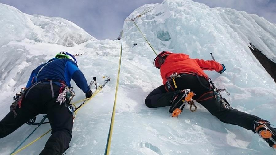 Eiskletterabenteuer am Arlberg Zwei Kletterer steigen eine senkrechte Eiswand mit Kletterausrüstung empor und nutzen Seile.