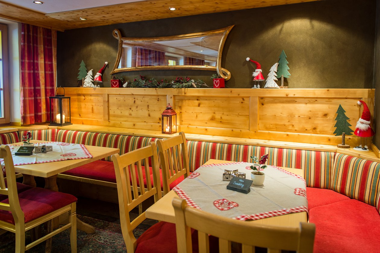 Gemütliches Restaurantambiente zur Feiertagszeit Die gemütliche Stube mit Holzmöbeln, roten Sitzpolstern und warmem Licht im Tannbergerhof in Lech