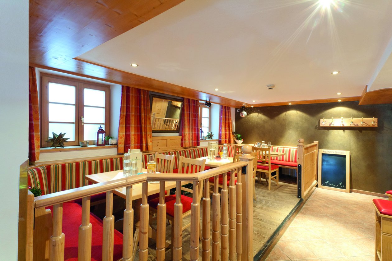 Gemütliches Restaurantinterieur im Tannbergerhof Die gemütliche Stube im Tannbergerhof in Lech mit Holzmöbeln, roten Sitzpolstern und warmem Licht