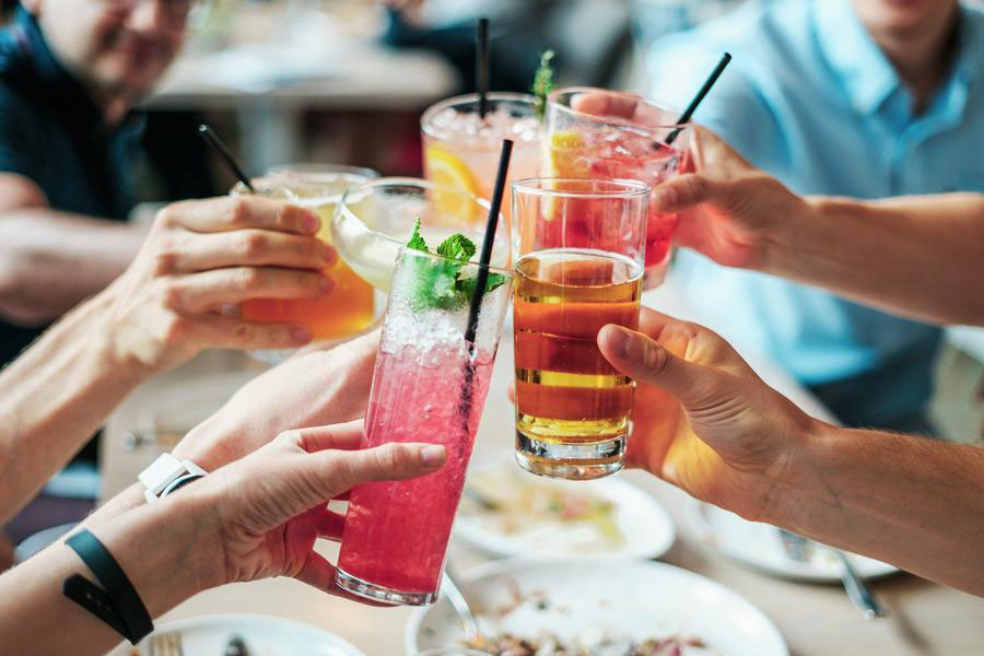 Freunde stoßen mit Cocktails an Menschen die mit Alkoholische Getränken anstoßen