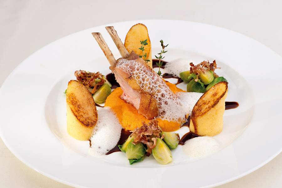 Gourmetgericht mit Lammrücken Lammkarree, Kartoffelbeilagen, Kürbispüree und Rosenkohl auf einem weißen Teller m Restaurant im Tannbergerhof in Lech © Foto Lehmann