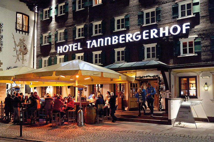 Verwöhnen Sie Ihren Gaumen mit ausgewählten Drinks Terrasse im Tannbergerhof mit Außenbar in der Menschen sitzen und feiern.