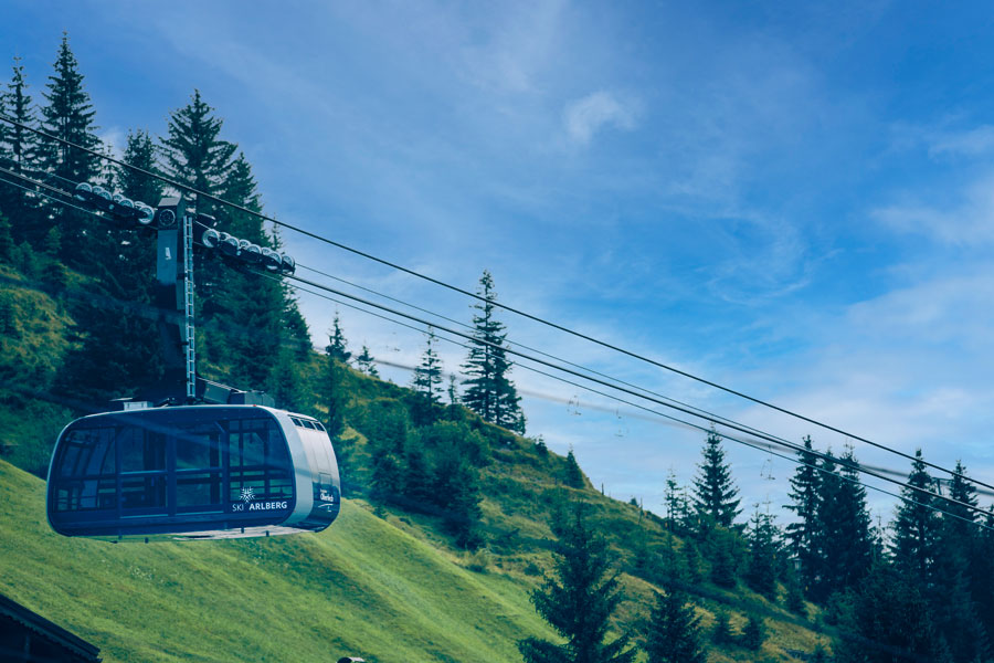 Seilbahn über grüne Berge Moderne Seilbahnkabine der Ski Arlberg Bahn schwebt über eine grüne Berglandschaft © Daniel Zangerl