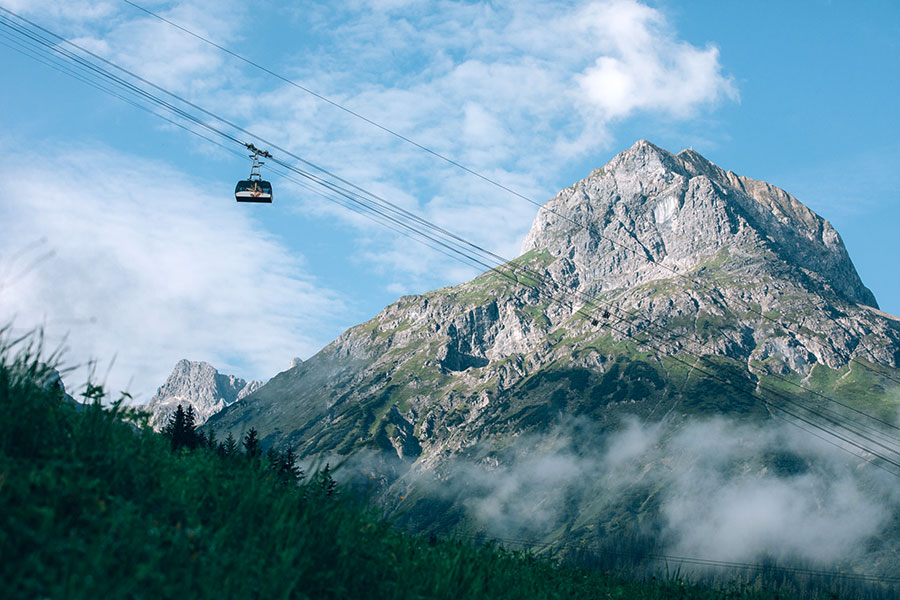 Sommerliche Berglandschaft mit Seilbahn Moderne Seilbahnkabine der Ski Arlbergbahn schwebt über einer grünen Berglandschaft © Daniel Zangerl