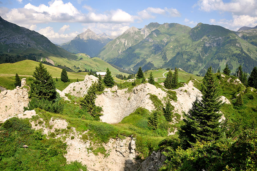 Alpine Landschaft entdecken Alpine Landschaft in Lech am Arlberg mit grünen Wiesen, Felsen und Bergpanorama im Hintergrund