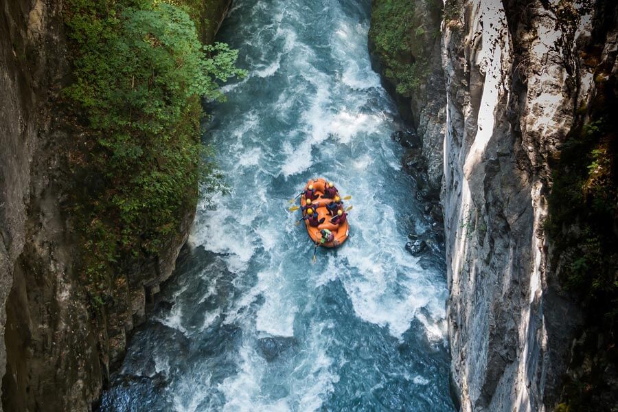 Spaß & Action im Wildwasser an heißen Sommertagen Eine Gruppe sitzt in einem Rafting Boot auf einem Wildwasserfluss