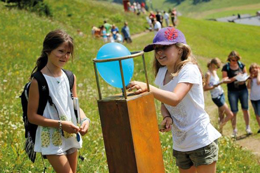 Familienwanderung am Grünen Rätselring Kinder forschen gerade an einer Station mit einem Luftballon nach der Lösung des Rätsel.