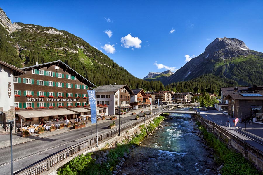 Alpenblick vom Tannbergerhof Außenansicht vom Hotel Tannbergerhof in Lech am Arlberg, direkt an einem klaren Gebirgsbach, mit Vorarlberger Bergkulisse im Hintergrund