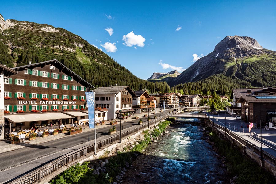 Naturerlebnis am Fluss Hotel in den Alpen mit Blick auf einen Fluss und umliegende Berge und Bäume im Hintergrund.