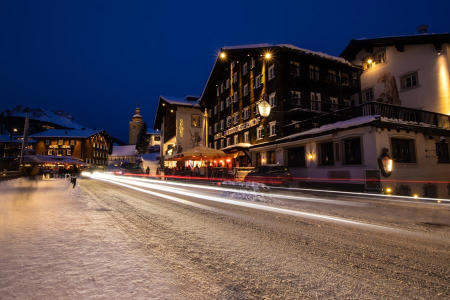 Winteridylle im Alpenraum Schneebedecktes Dorf mit traditionellen alpinen Gebäuden bei Nacht, beleuchtet von warmem Licht