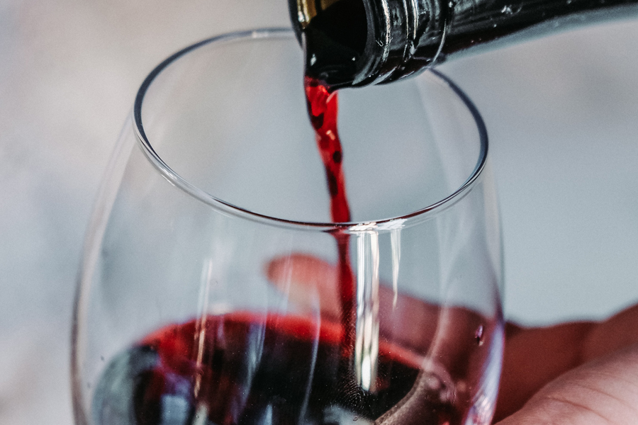 Weinberg-Event im Dezember Weinglas in das gerade Rotwein eingeschenkt wird.