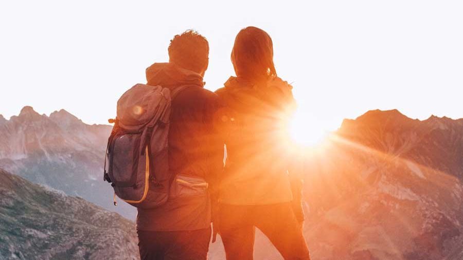 Romantische Bergsonne erleben Paar steht auf einem Berg und betrachtet den Sonnenuntergang über der Landschaft