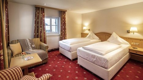 Gemütliches Doppelzimmer im Tannbergerhof Hotelzimmer mit zwei Einzelbetten und einem Sitzbereich mit Tisch und Stuhl in gemütlicher Atmosphäre