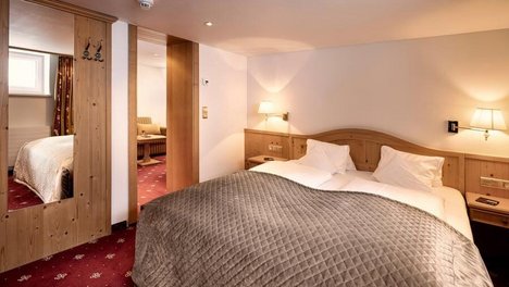 Komfortable Familien Suite im Tannbergerhof Behagliches Schlafzimmer mit Doppelbett und Holz Möbeln in einer Hotel Suite in Lech.
