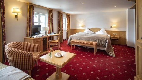 Luxuriöses Doppelzimmer für erholsame Nächte Geräumiges Hotelzimmer mit großem Bett, Sitzbereich und Schreibtisch mit Computer